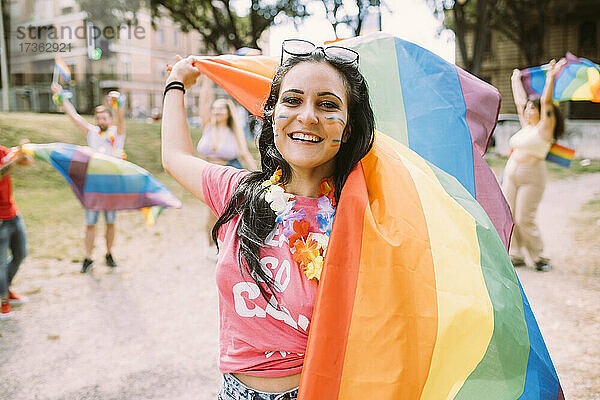 Glückliche Frau mit Regenbogenfahne bei Pride-Veranstaltung  um für Gleichberechtigung zu protestieren