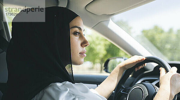 Frau im Hidschab schaut beim Autofahren weg