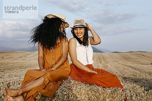 Lächelnde Frauen mit Hut auf einem Feld sitzend