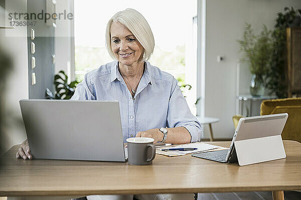 Reife Geschäftsfrau arbeitet am Laptop im Büro zu Hause