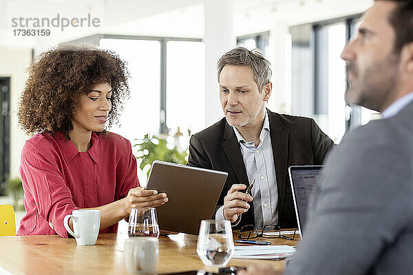 Kollegen mit digitalem Tablet diskutieren während der Arbeit in einer Besprechung