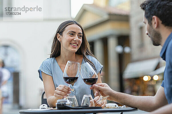 Paar stößt mit Wein an  während es in einem Straßencafé sitzt