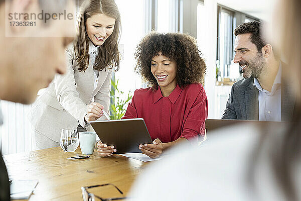 Geschäftsfrau nutzt digitales Tablet mit Kollegen in einer Besprechung im Büro