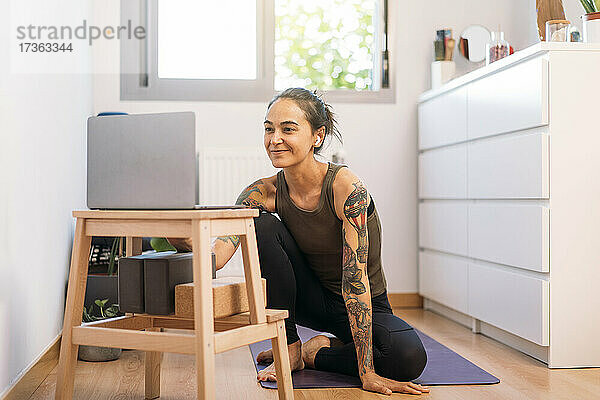 Frau e-learning Yoga durch Laptop zu Hause