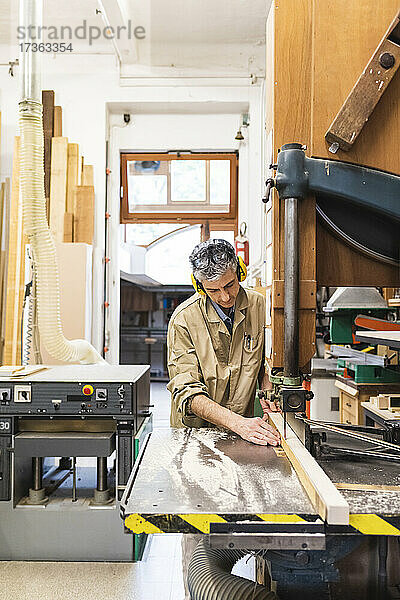 Reifer männlicher Tischler bei der Arbeit mit einer Maschine in der Werkstatt