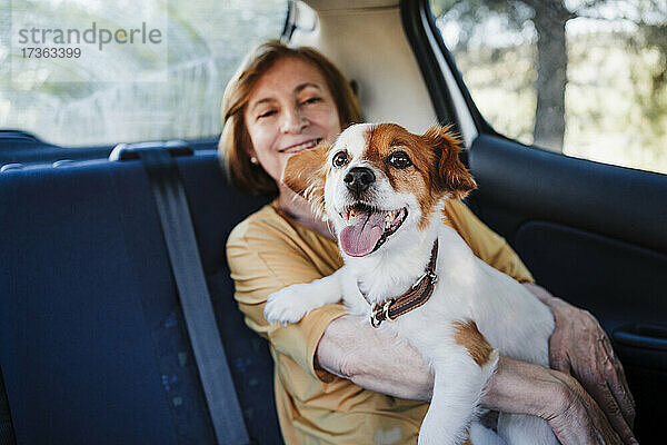 Ältere Frau mit Hund im Auto sitzend
