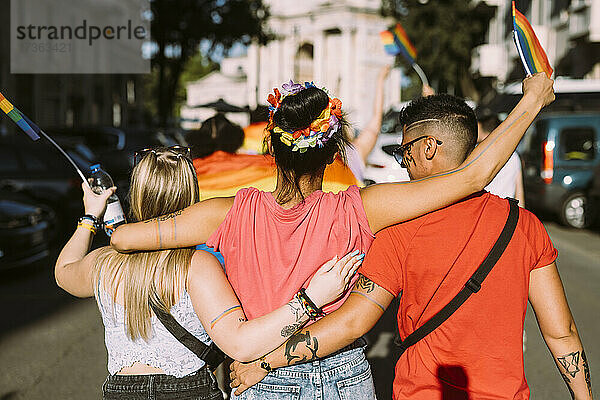 Multiethnische Freundinnen gehen auf der Straße während einer Pride-Veranstaltung