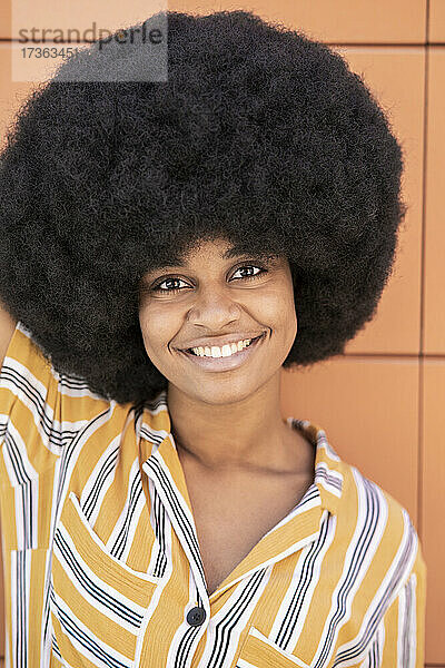 Afro-Frau lächelnd vor einer Wand