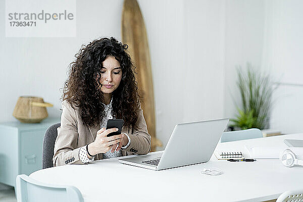 Geschäftsfrau benutzt Mobiltelefon bei der Arbeit im Büro