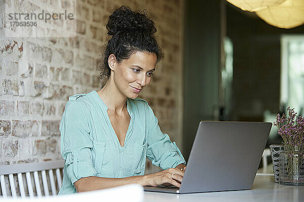 Berufstätige Frau benutzt Laptop bei der Arbeit im Büro
