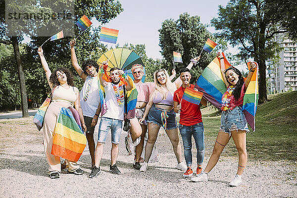 Fröhliche männliche und weibliche Freunde mit Regenbogenfahnen im Park