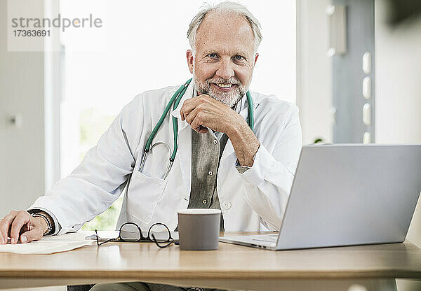 Lächelnde männliche medizinische Fachkraft am Schreibtisch