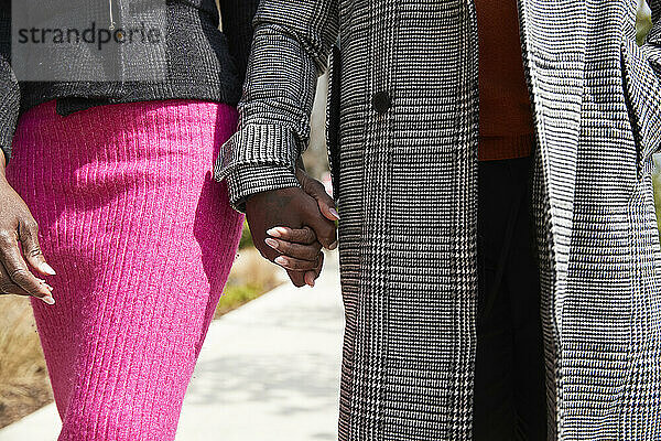 Paar hält Hände beim Spaziergang an einem sonnigen Tag
