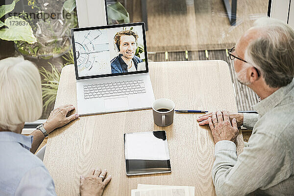Reife Geschäftsleute führen einen Videoanruf mit einem männlichen Kollegen am Laptop im Büro zu Hause