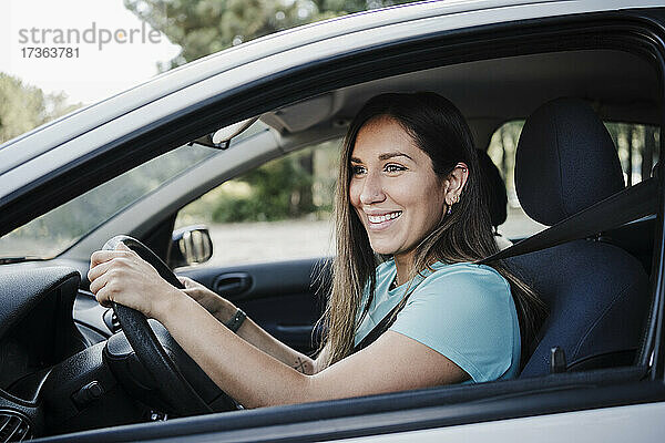 Lächelnde schöne Frau fährt Auto