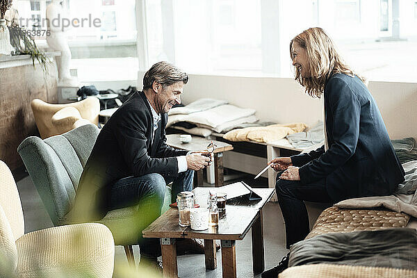 Glücklicher Geschäftsmann und Geschäftsfrau lachen  während sie in einem Café miteinander diskutieren