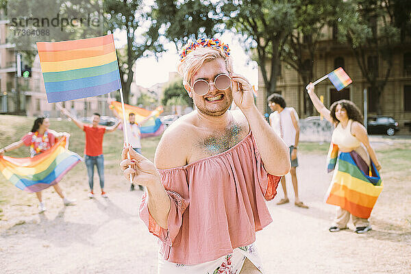 Lächelnder schwuler Mann mit Flagge im Park stehend