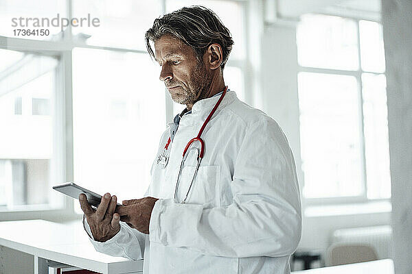 Männlicher Angestellter des Gesundheitswesens benutzt ein digitales Tablet in einer medizinischen Klinik