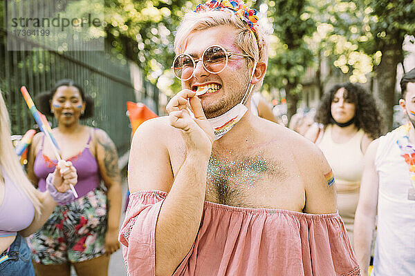Lächelnder schwuler Mann  der während einer Pandemie bei einer Pride-Veranstaltung isst
