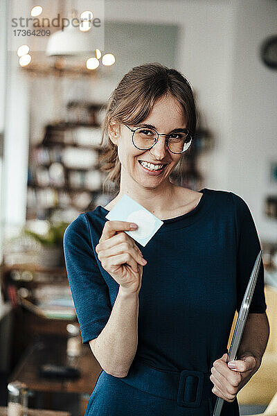 Glückliche Geschäftsfrau mit Laptop und Karte in einem Cafe