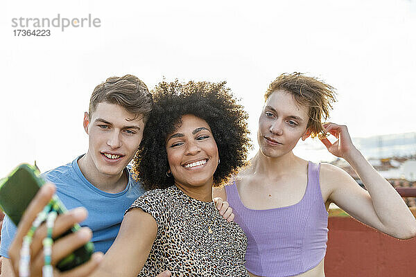 Männliche und weibliche Freunde nehmen Selfie durch Smartphone auf Terrasse