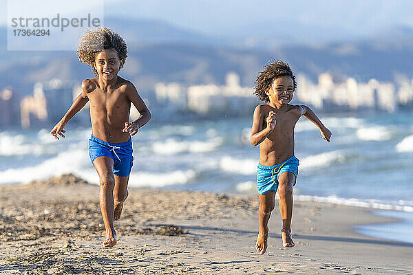 Fröhliche Brüder laufen zusammen am Strand
