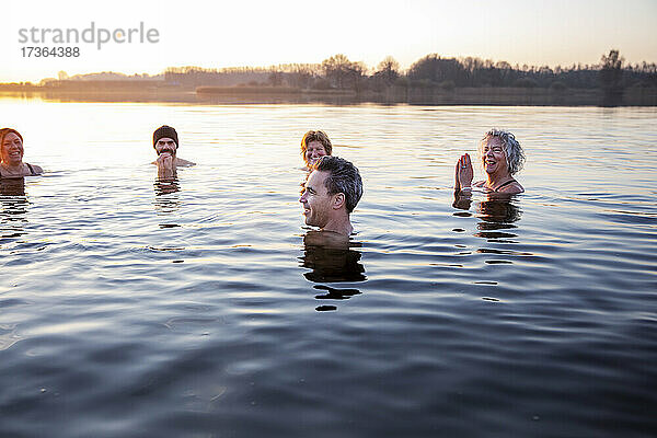 Lächelnde männliche und weibliche Freunde  die sich im kalten Wasser vergnügen