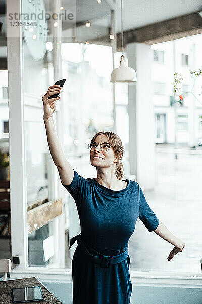 Junge Geschäftsfrau nimmt Selfie durch Smartphone im Café