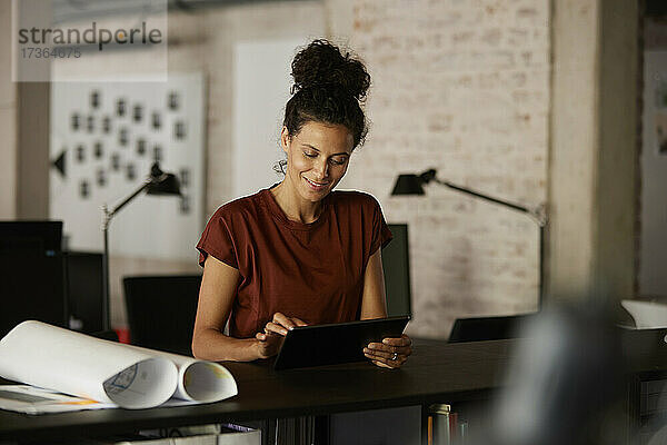 Weiblicher Berufstätiger mit digitalem Tablet am Schreibtisch im Büro
