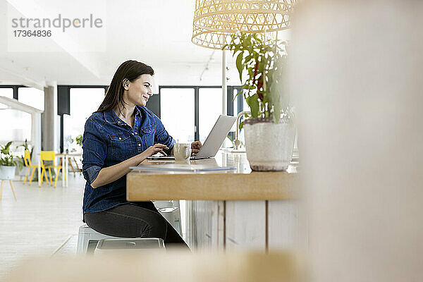 Berufstätige Frau benutzt Laptop bei der Arbeit im Büro