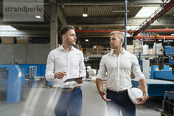 Männliche Fachleute diskutieren beim Gehen in einer Fabrik