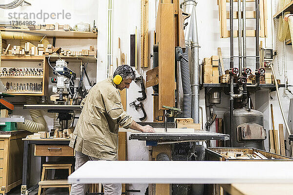 Älterer männlicher Handwerker bei der Arbeit mit Maschinen in einer Werkstatt
