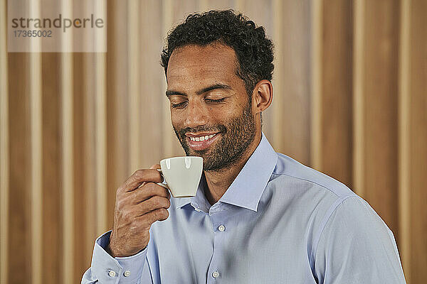 Lächelnde männliche Fachkraft hält Kaffeetasse im Büro