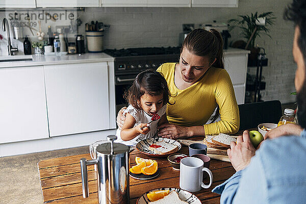 Eltern betrachten ihre Tochter beim Frühstück zu Hause