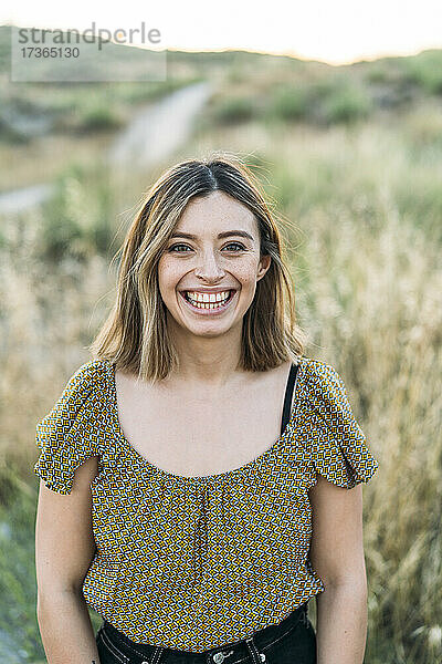Junge Frau lächelt  während sie auf einem Feld steht