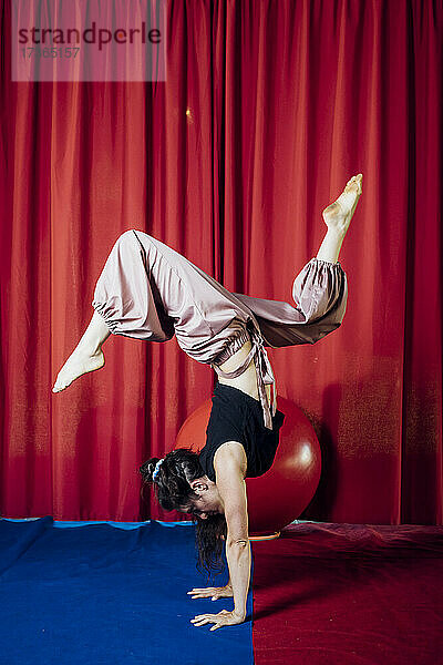 Weiblicher Akrobat im Handstand auf der Zirkusbühne