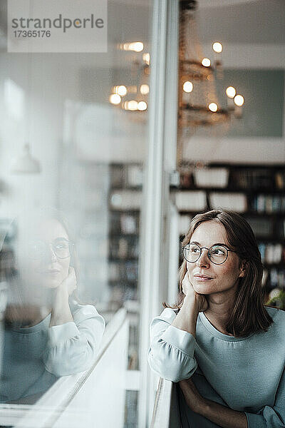 Nachdenkliche junge Frau  die durch das Fenster schaut  während sie in einem Cafe sitzt