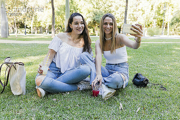 Lächelnde Freundinnen machen ein Selfie mit ihrem Smartphone im Park