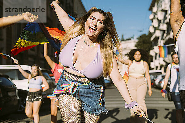 Fröhliche Frau mit männlichen und weiblichen Freunden protestiert an einem sonnigen Tag bei einer Pride-Veranstaltung