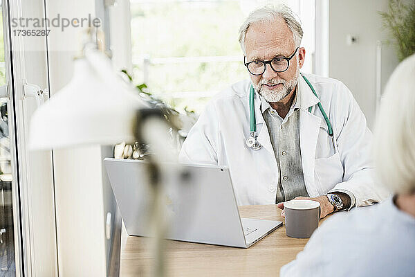 Männlicher Arzt mit Laptop am Schreibtisch