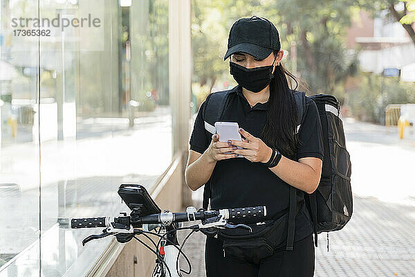 Weiblicher Zusteller mit Gesichtsschutzmaske und Smartphone