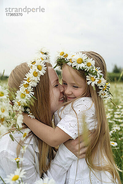 Lächelnde Mutter und Tochter mit Blumen auf einem Feld