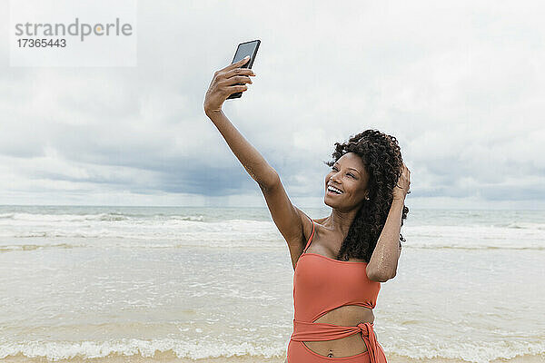 Glückliche schöne Frau nimmt Selfie durch Handy am Strand