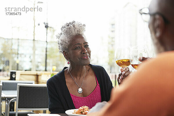 Lächelnde Frau stößt mit einem Mann im Restaurant auf ein Getränk an