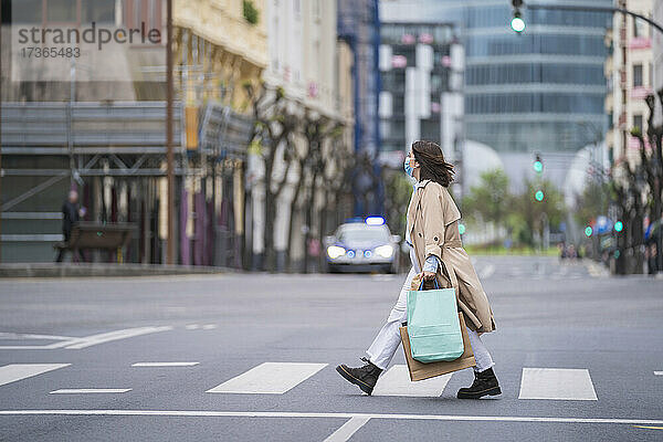 Frau überquert Straße mit Einkaufstüten während der Pandemie