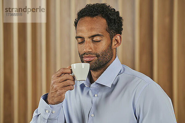 Geschäftsmann riecht Kaffeeduft aus einer Tasse im Sitzungssaal