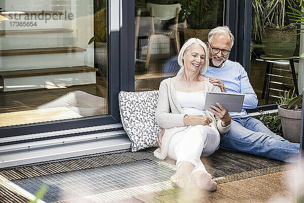 Frau benutzt digitales Tablet  während sie neben einem Mann auf dem Balkon sitzt