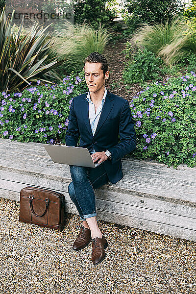 Geschäftsmann mit Laptop im Park sitzend