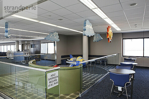 Ein Kinderspielbereich in der Abflughalle des Flughafens mit Schildern. Tische und Stühle.