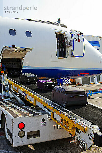 Ein Passagierflugzeug am Boden  das Gepäck wird auf ein laufendes Band geladen